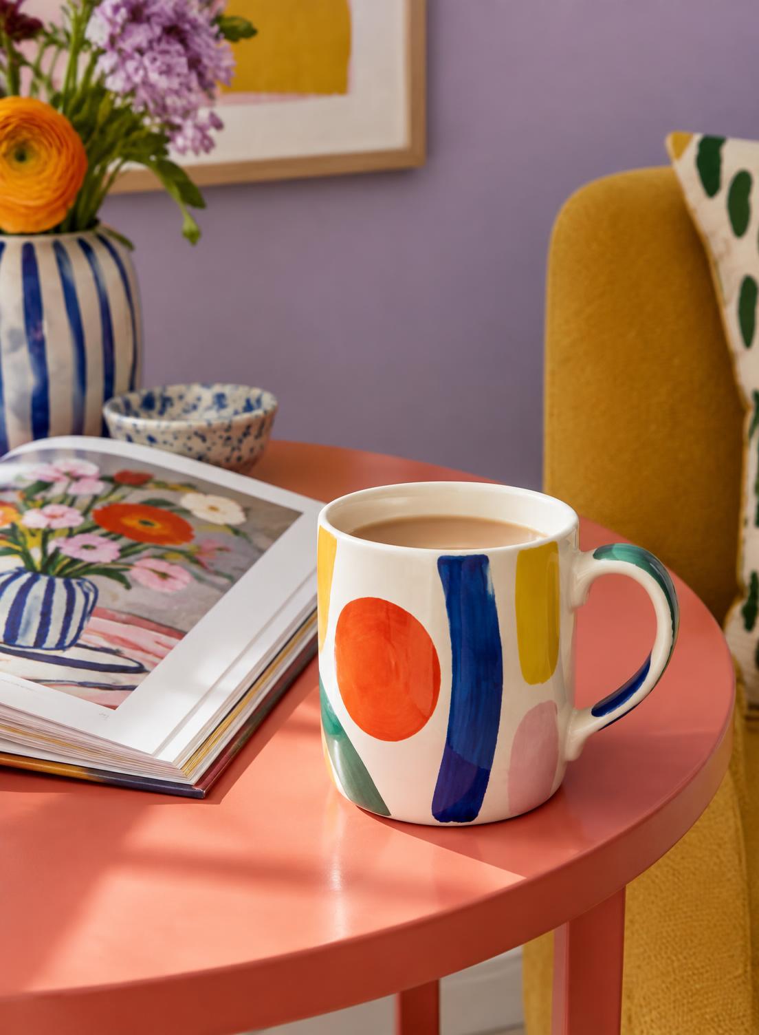 Colourful mug with tea beside an art book